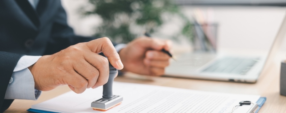Businessman signing and stamping official document at desk, concept of legal contract approval, authorization or business agreement confirmation in corporate office background. stamp approval