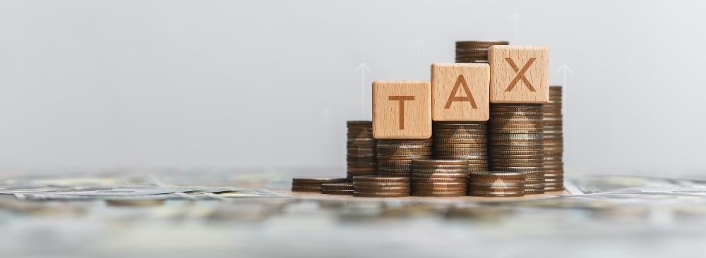 Stack of silver coins with wooden blocks word Tax.